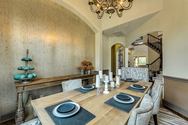 2104 University Club Dr, Austin, TX 78732 - dining area with arched walkways, wood finished floors, a chandelier, stairway, and a high ceiling