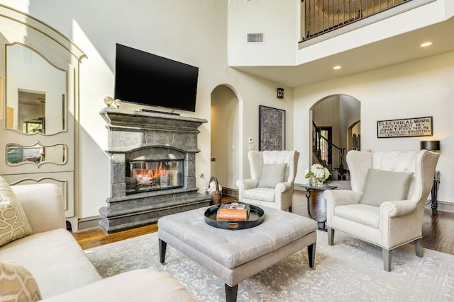 2104 University Club Dr, Austin, TX 78732 - living area featuring arched walkways, wood finished floors, a glass covered fireplace, a high ceiling, and recessed lighting
