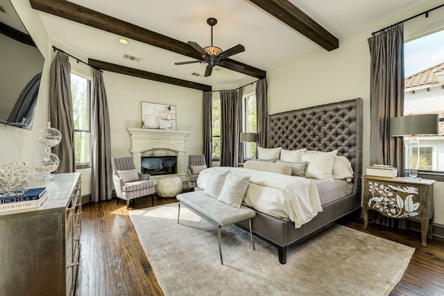 2104 University Club Dr, Austin, TX 78732 - bedroom featuring multiple windows, beamed ceiling, dark wood-style flooring, a glass covered fireplace, and a ceiling fan