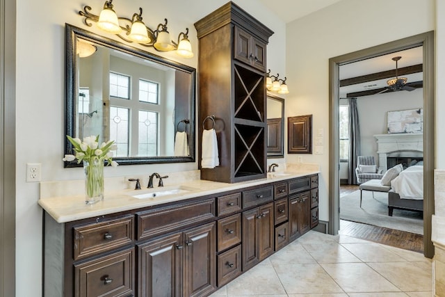 2104 University Club Dr, Austin, TX 78732 - ensuite bathroom with double vanity, ceiling fan, a fireplace, tile patterned floors, and beamed ceiling