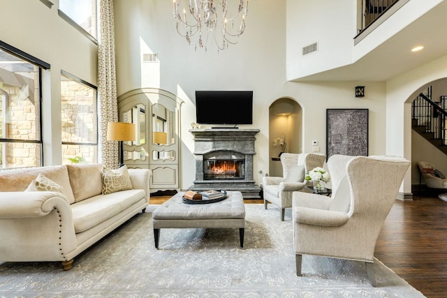 2104 University Club Dr, Austin, TX 78732 - living room featuring wood finished floors, a towering ceiling, a chandelier, arched walkways, and a lit fireplace