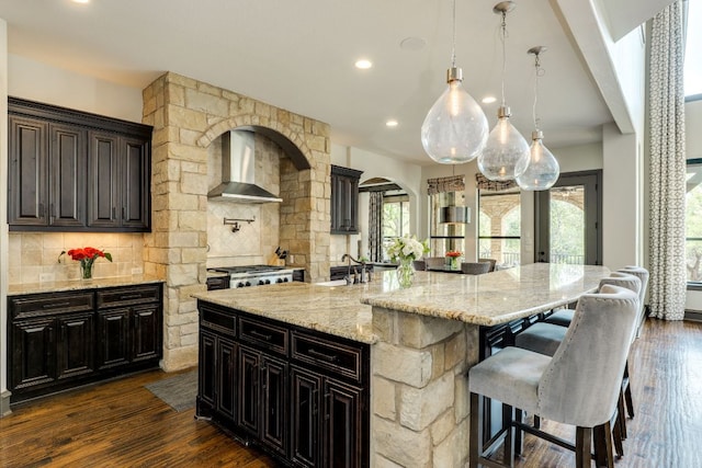 2104 University Club Dr, Austin, TX 78732 - kitchen featuring wall chimney exhaust hood, tasteful backsplash, a sink, a kitchen breakfast bar, and recessed lighting