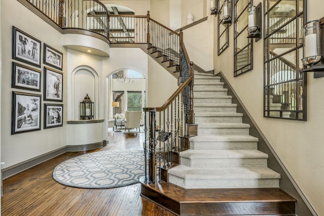 2104 University Club Dr, Austin, TX 78732 - stairs with a towering ceiling, wood-type flooring, a chandelier, baseboards, and arched walkways