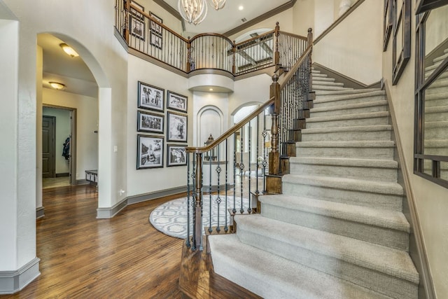 2104 University Club Dr, Austin, TX 78732 - stairs featuring arched walkways, a high ceiling, wood finished floors, baseboards, and a chandelier