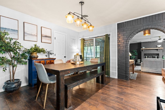 26 N Castleberry St, Lampasas, TX 76550 - dining space with arched walkways, a brick fireplace, a chandelier, and dark wood-style floors