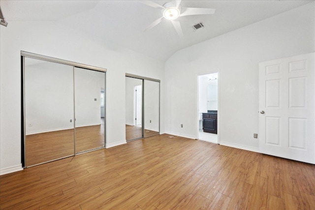 unfurnished bedroom with ensuite bathroom, multiple closets, light wood-style floors, lofted ceiling, and visible vents