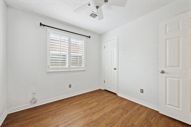 unfurnished bedroom with wood finished floors, visible vents, a closet, baseboards, and a textured ceiling