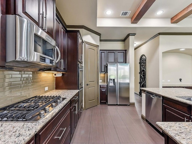 6120 Gunnison Turn Rd, Austin, TX 78738 - kitchen with appliances with stainless steel finishes, beam ceiling, tasteful backsplash, arched walkways, and light stone countertops