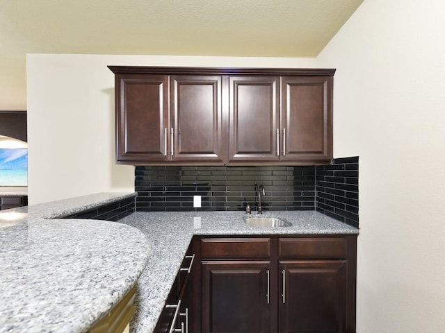 6120 Gunnison Turn Rd, Austin, TX 78738 - kitchen featuring a sink, tasteful backsplash, dark brown cabinetry, and light stone counters