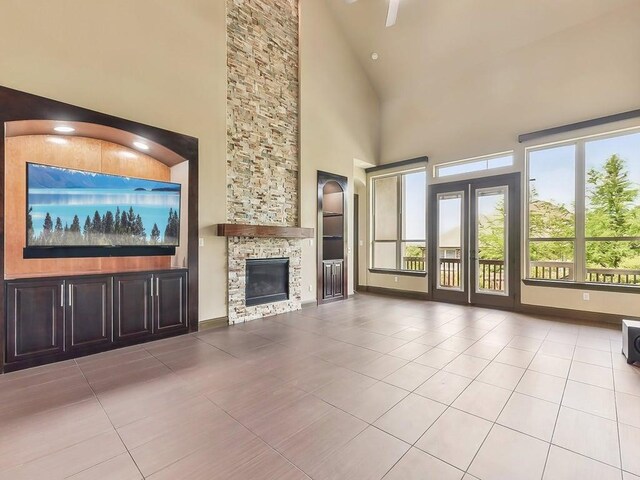 6120 Gunnison Turn Rd, Austin, TX 78738 - unfurnished living room with tile patterned floors, high vaulted ceiling, a stone fireplace, and baseboards