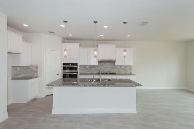 313 Singing Dove Way, Liberty Hill, TX 78642 - kitchen with dark stone counters, a sink, decorative backsplash, an island with sink, and stainless steel double oven