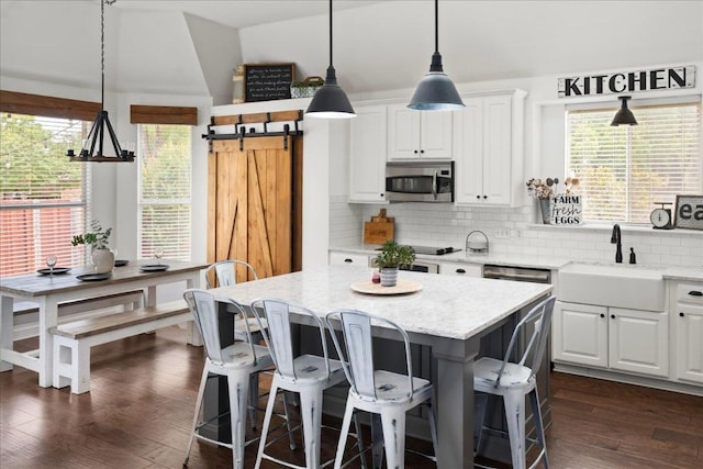 134 Brentwood Dr, Georgetown, TX 78628 - kitchen featuring stainless steel microwave, a sink, white cabinetry, decorative backsplash, and a center island