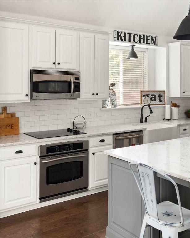 134 Brentwood Dr, Georgetown, TX 78628 - kitchen featuring appliances with stainless steel finishes, white cabinets, a sink, tasteful backsplash, and light stone counters