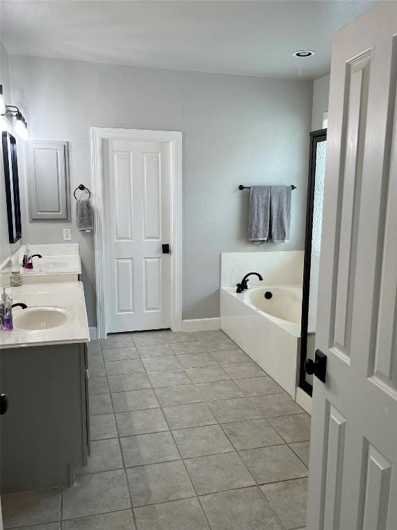 134 Brentwood Dr, Georgetown, TX 78628 - bathroom with tile patterned flooring, a garden tub, double vanity, and baseboards