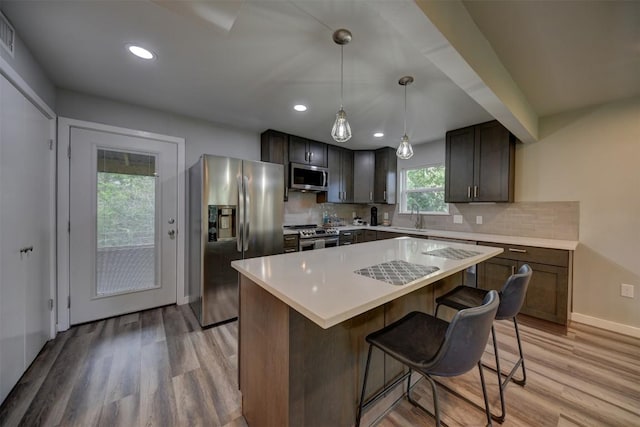 417 Big Bow, Smithville, TX 78957 - kitchen with a sink, tasteful backsplash, light wood-type flooring, a kitchen island, and appliances with stainless steel finishes