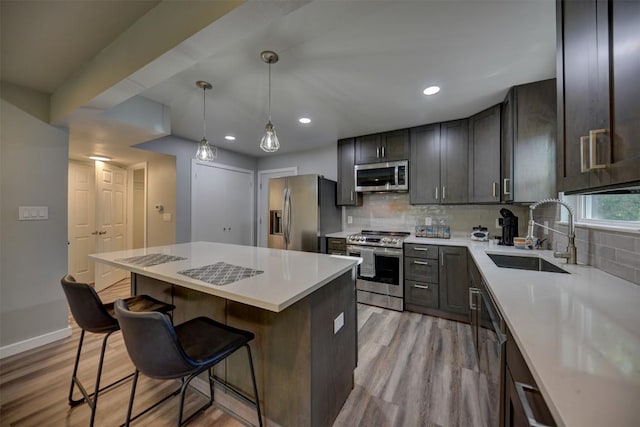 417 Big Bow, Smithville, TX 78957 - kitchen with a sink, decorative backsplash, a breakfast bar area, stainless steel appliances, and light wood finished floors