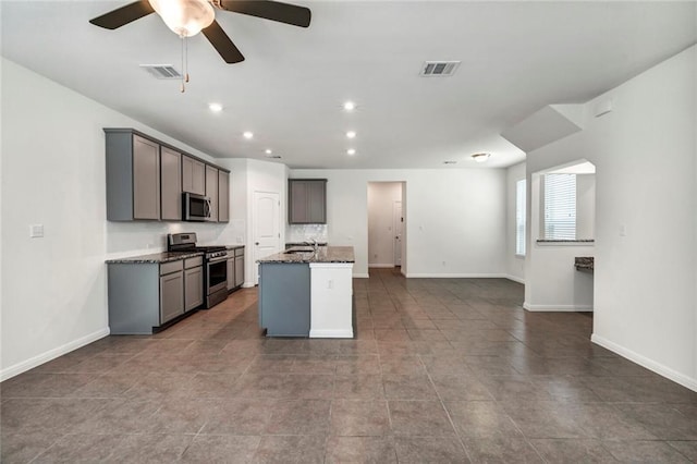 265 Spanish Star Trl, Dripping Springs, TX 78620 - kitchen with stainless steel appliances, open floor plan, a ceiling fan, dark stone counters, and an island with sink