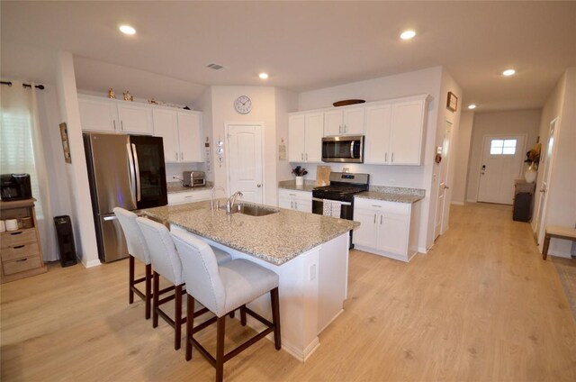 2504 Indian Clover Trl, Leander, TX 78641 - kitchen featuring stainless steel appliances, a kitchen breakfast bar, a sink, white cabinets, and an island with sink
