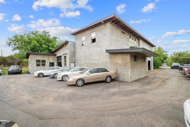 view of side of property with stucco siding and uncovered parking