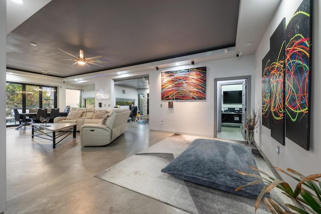 living area with ceiling fan and finished concrete flooring