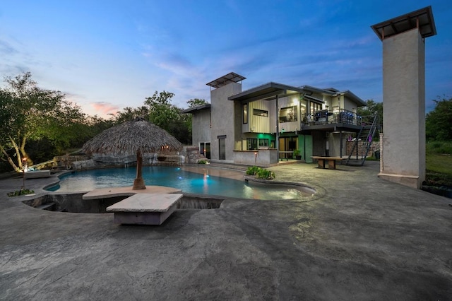 pool at dusk featuring an outdoor pool and a patio area