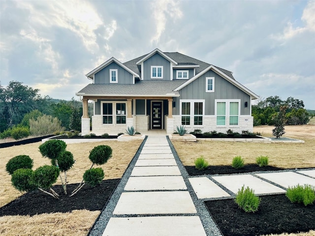1603 Headwaters Blvd, Dripping Springs, TX 78620 - craftsman house with stone siding, covered porch, a shingled roof, board and batten siding, and a front yard