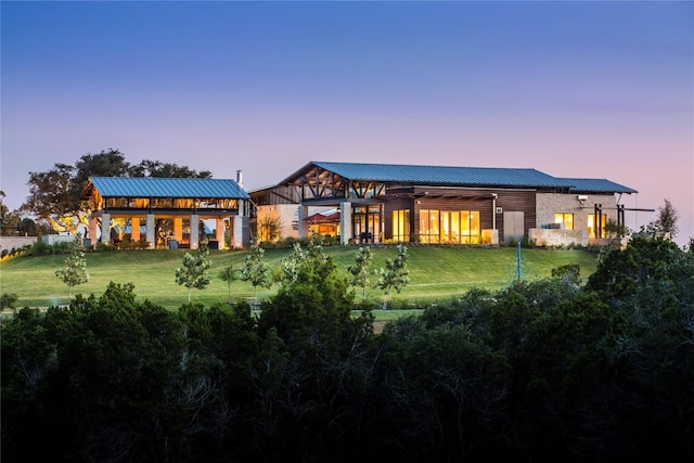 1603 Headwaters Blvd, Dripping Springs, TX 78620 - back of property featuring a lawn, a standing seam roof, stone siding, and metal roof