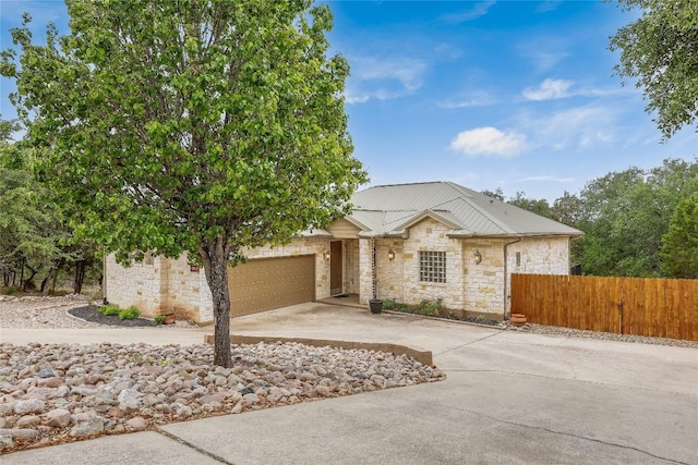5004 Arrowhead Dr, Lago Vista, TX 78645 - view of front of home with stone siding, fence, concrete driveway, an attached garage, and metal roof