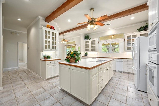 kitchen with a wealth of natural light, beamed ceiling, a ceiling fan, white appliances, and light tile patterned floors