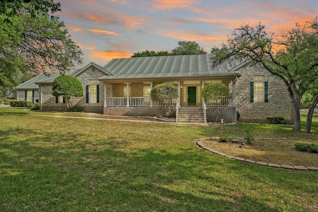 view of front facade with a lawn, a porch, and stone siding