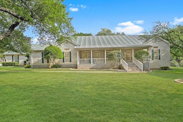 view of front facade with stone siding, a front lawn, covered porch, and metal roof