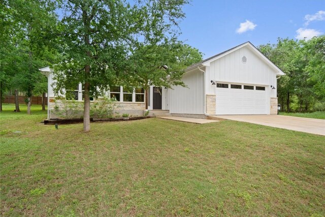 ranch-style house featuring stone siding, a front lawn, driveway, and an attached garage