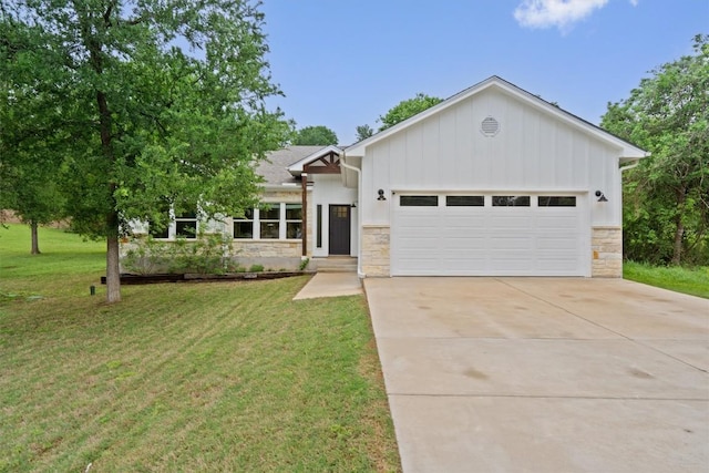 view of front of house featuring driveway, a garage, a front yard, and stone siding