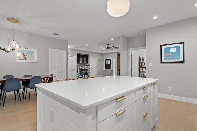 kitchen featuring ceiling fan, baseboards, a tile fireplace, recessed lighting, and light wood finished floors