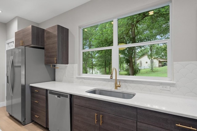 kitchen featuring decorative backsplash, stainless steel appliances, light countertops, dark brown cabinets, and a sink