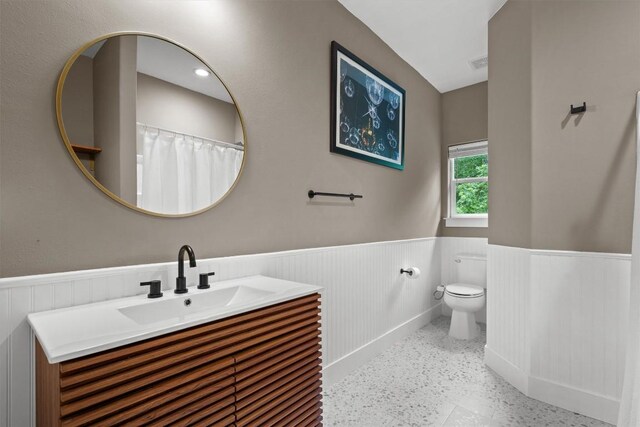 bathroom with visible vents, a wainscoted wall, toilet, and vanity