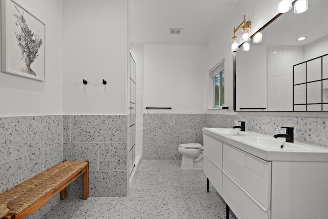 full bath featuring visible vents, toilet, a wainscoted wall, and tile walls