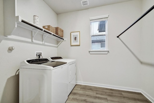 clothes washing area featuring light wood-style flooring, baseboards, visible vents, separate washer and dryer, and laundry area