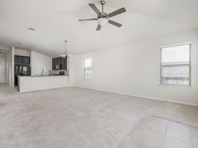 180 Tailwind Dr, Kyle, TX 78640 - unfurnished living room featuring vaulted ceiling, a ceiling fan, light carpet, and a chandelier