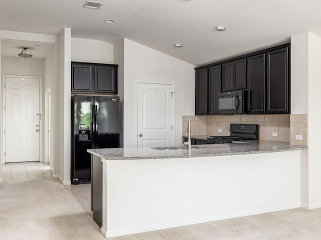 180 Tailwind Dr, Kyle, TX 78640 - kitchen with black appliances, light stone counters, vaulted ceiling, a peninsula, and light colored carpet