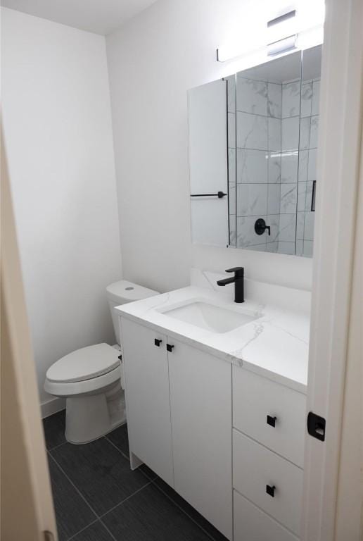 bathroom with tile patterned flooring, toilet, vanity, and tiled shower