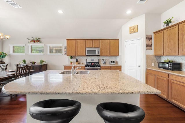 535 Tranquility Mtn, Buda, TX 78610 - kitchen featuring stainless steel appliances, a sink, a breakfast bar, decorative backsplash, and light stone countertops