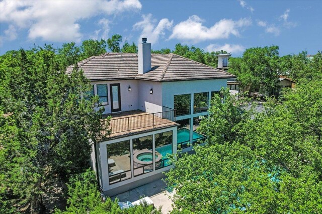 5711 Pool Canyon Cv, Austin, TX 78734 - rear view of property featuring stucco siding, a chimney, a pool with connected hot tub, and a tiled roof