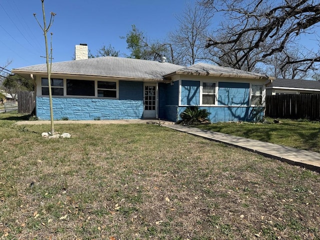 ranch-style home with concrete block siding, a front lawn, stone siding, a chimney, and fence