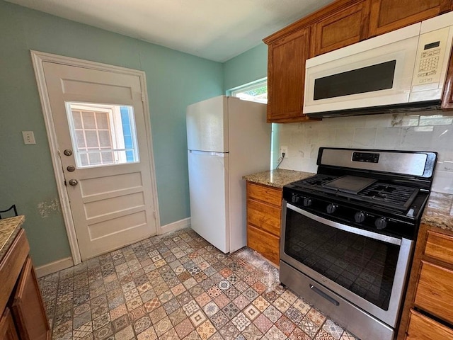1120 Fisher St, Taylor, TX 76574 - kitchen with white appliances, brown cabinetry, decorative backsplash, and light stone counters