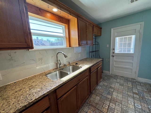 kitchen featuring baseboards, decorative backsplash, and a sink