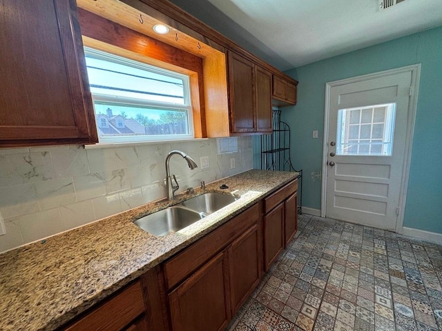 1120 Fisher St, Taylor, TX 76574 - kitchen featuring tasteful backsplash, brown cabinets, and light stone countertops