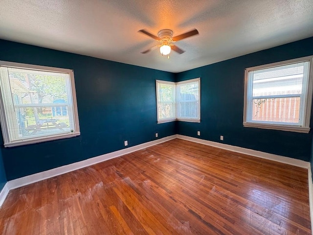 spare room featuring wood-type flooring, a wealth of natural light, and ceiling fan