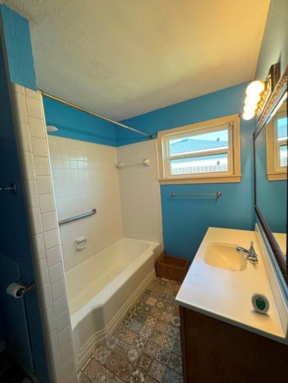 bathroom with shower / bath combination, vanity, and a textured ceiling