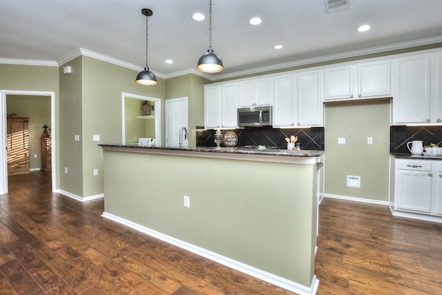 802 Apache Mountain Ln, Georgetown, TX 78633 - kitchen featuring stainless steel microwave, white cabinetry, ornamental molding, dark wood-style flooring, and decorative backsplash